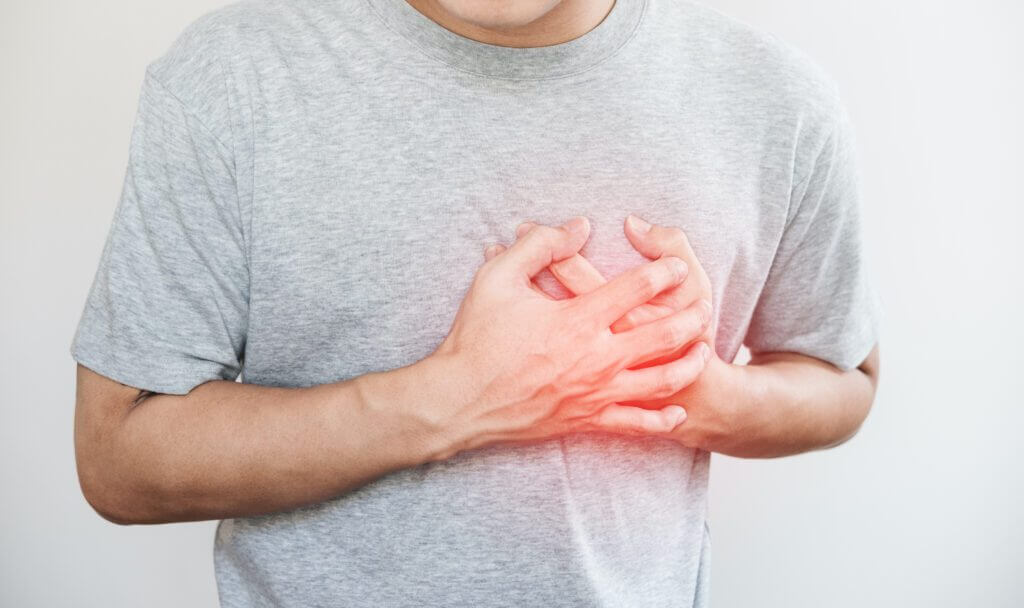 a man touching his heart with red highlight of heart attack