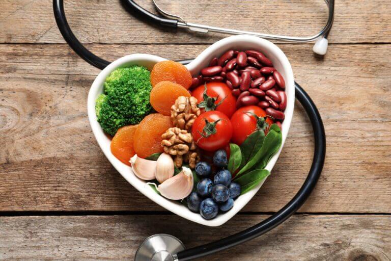 Bowl with products for heart-healthy diet and stethoscope