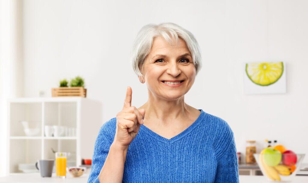 smiling senior woman pointing finger up